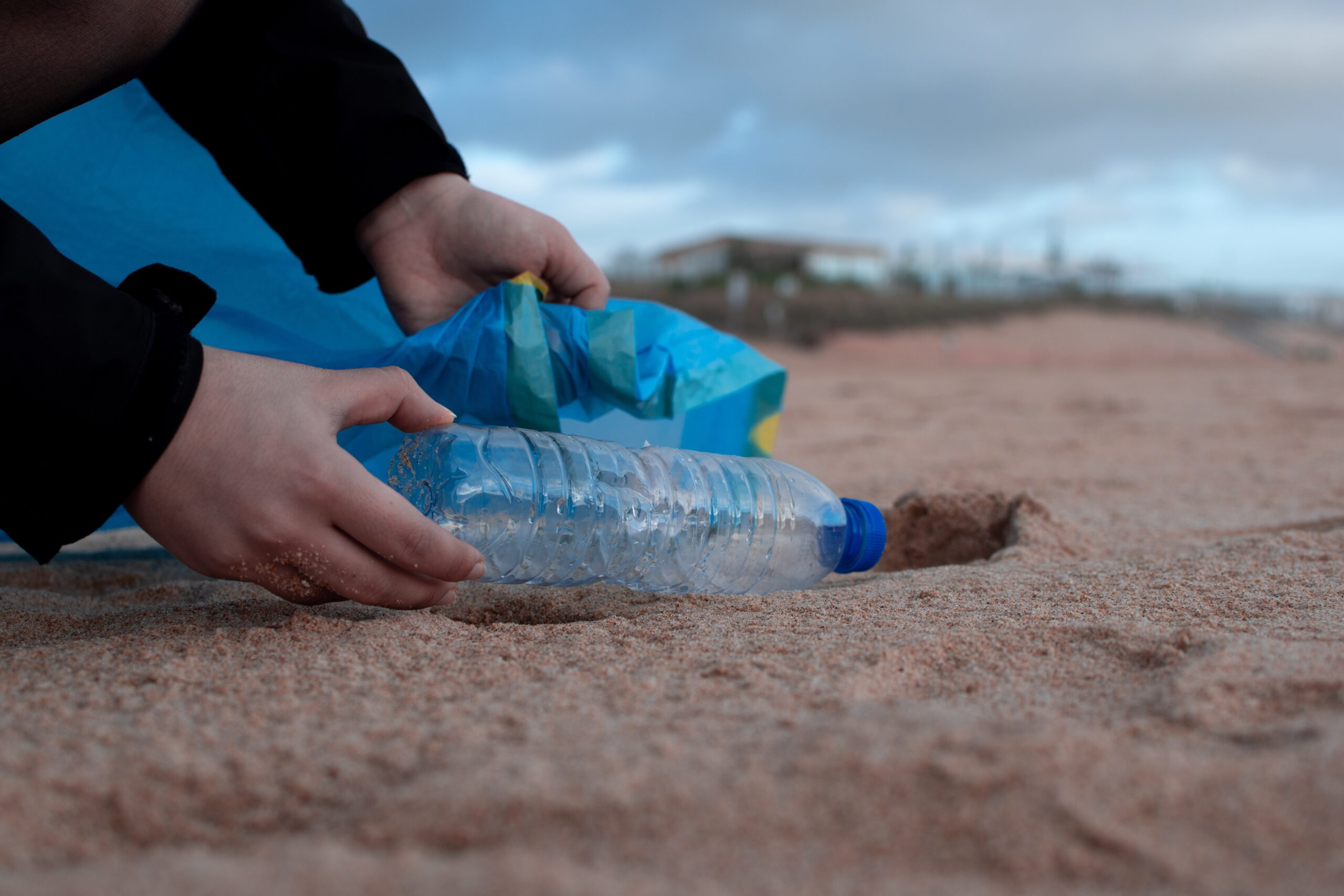 man picking up plastic bottle in a seashore