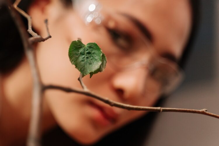 woman looking at single leave of a branch